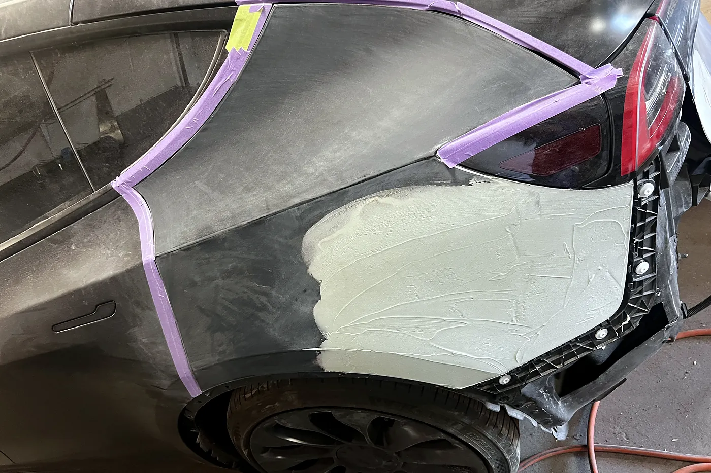 Rear quarter panel masked with tape and skimmed with body filler during a precision panel repair at Sultan Motors