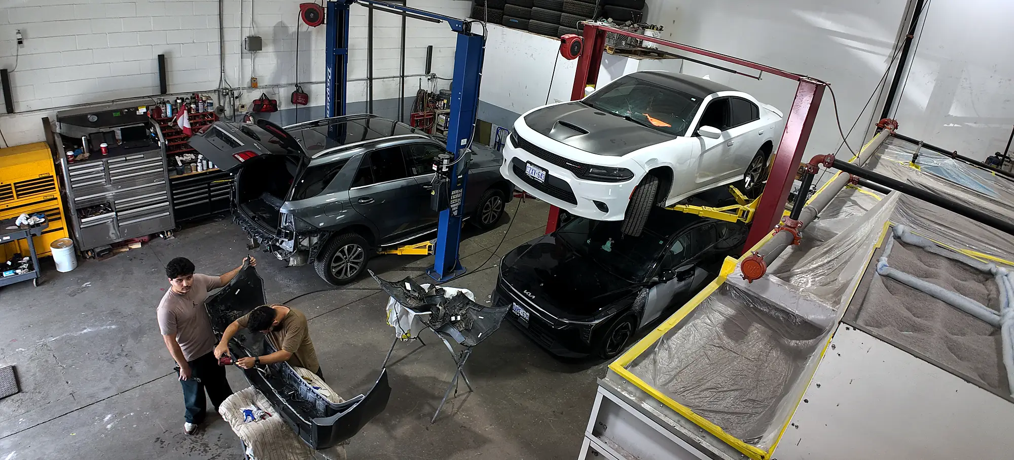 Wide view of the Sultan Motors collision repair bay in Brampton with vehicles on hoists and technicians at work