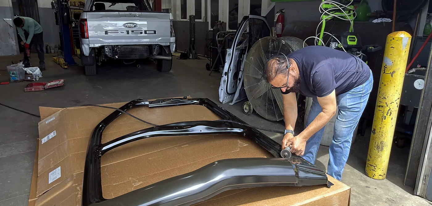 Sultan Motors technician working a replacement roof panel with a hand tool inside the Brampton workshop