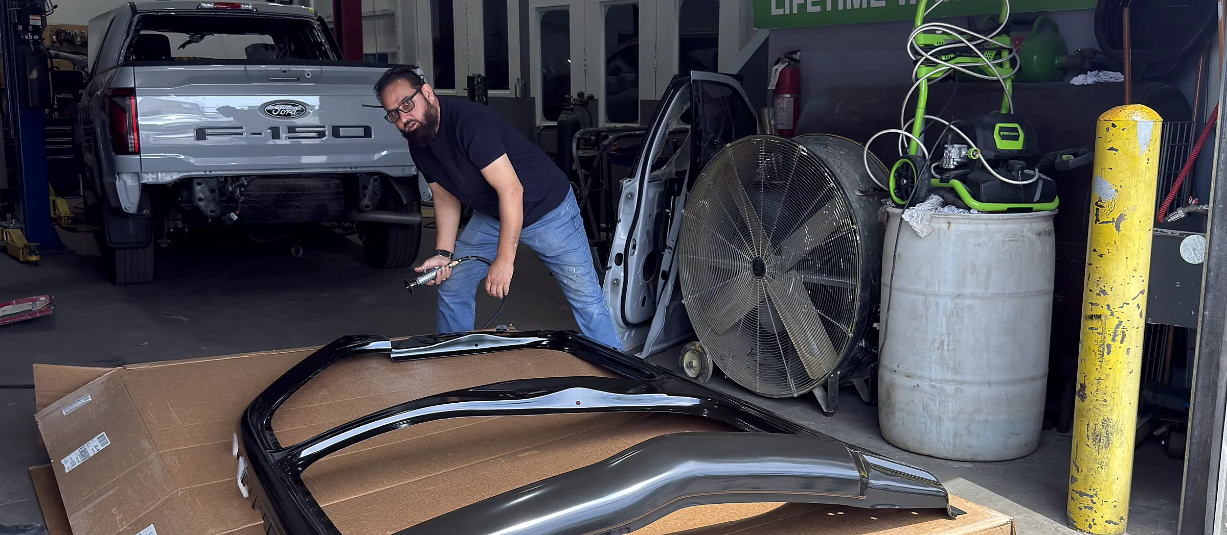 Sultan Motors technician inspecting a new roof panel assembly beneath the shop's branded signage