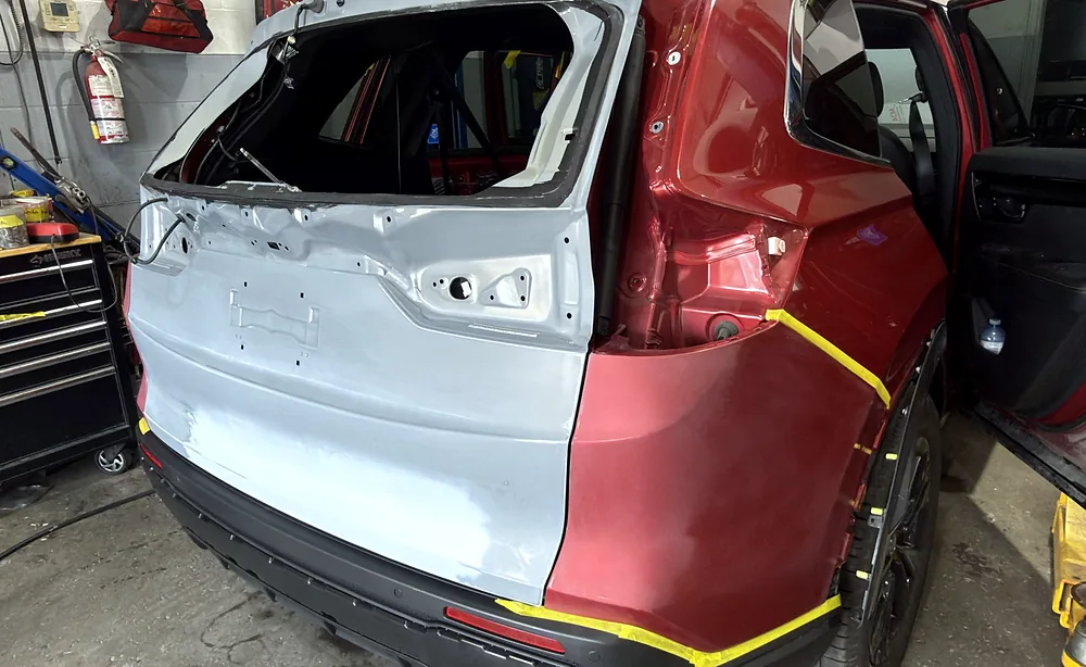 SUV rear quarter panel half in original colour and half in primer, masked for a blended paint repair