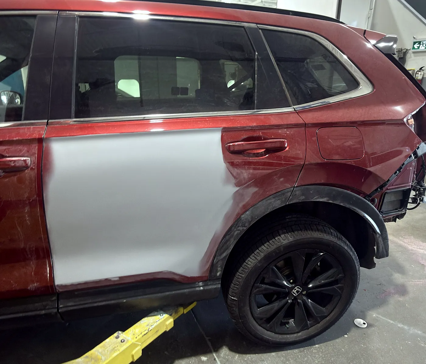 Honda CR-V fitted with an unpainted replacement door panel next to the original paint before refinishing