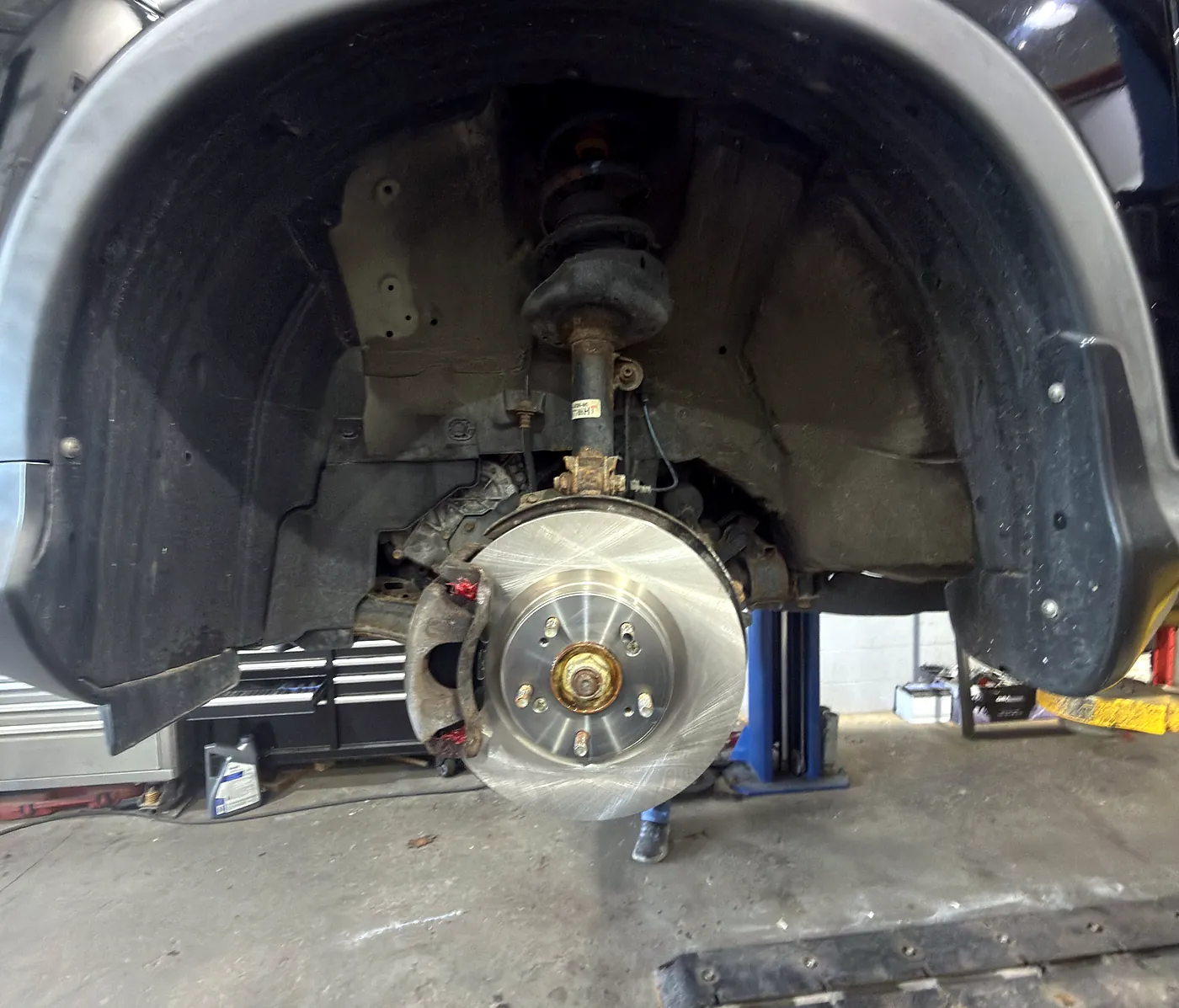 Brake rotor, hub and CV axle exposed in the wheel well with the wheel removed at Sultan Motors