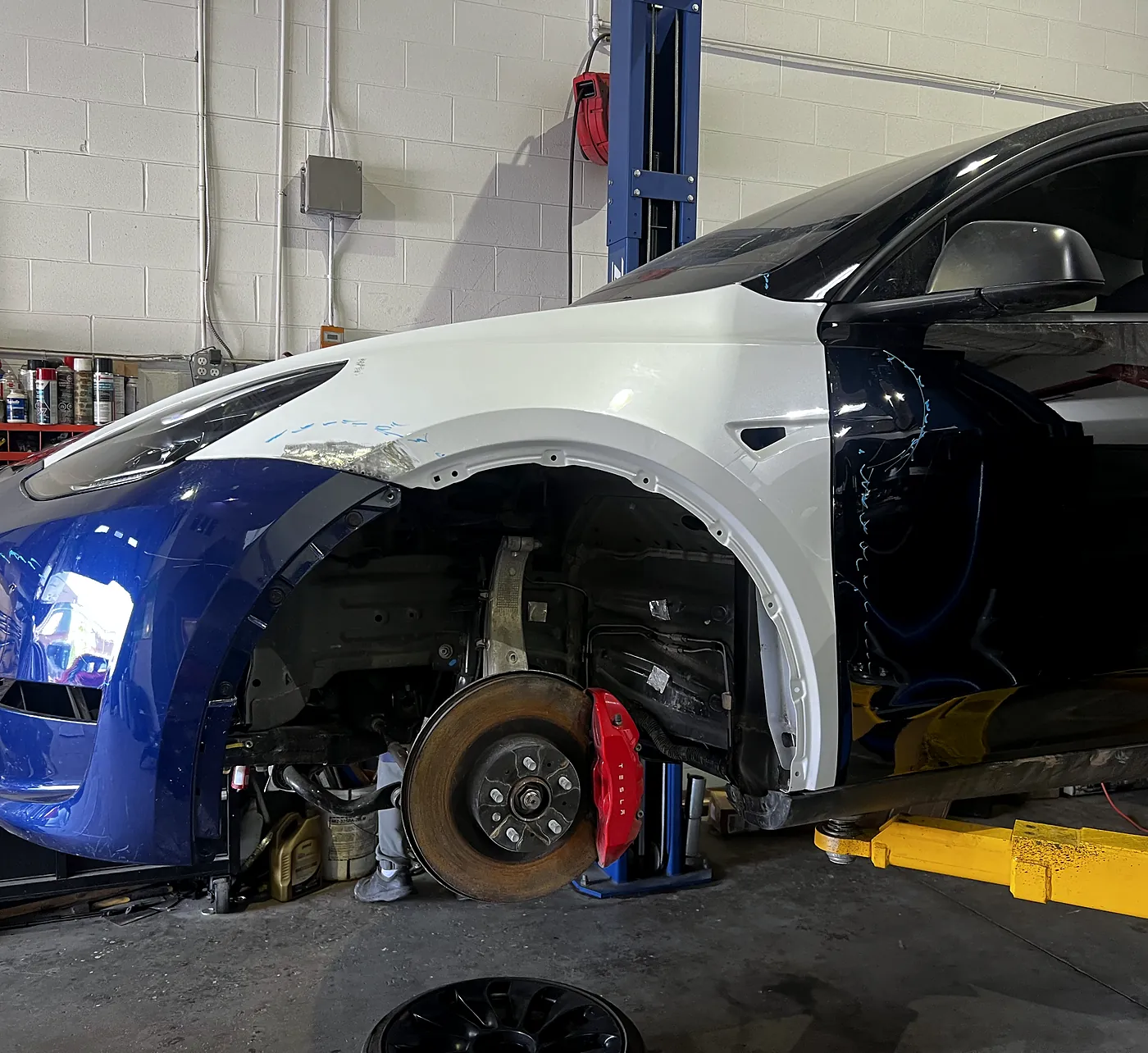 Front brake rotor and red caliper exposed on a Tesla Model Y with the wheel removed