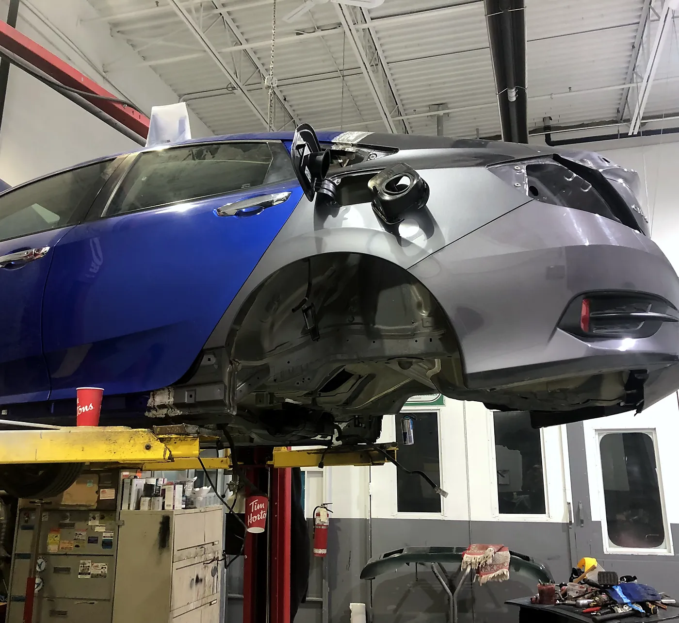 Structural splice in progress with a replacement front clip joined to the rear body section on the hoist