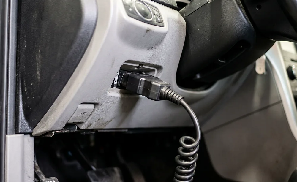 Close view of a diagnostic scan tool connector seated in a vehicle's OBD-II diagnostic port