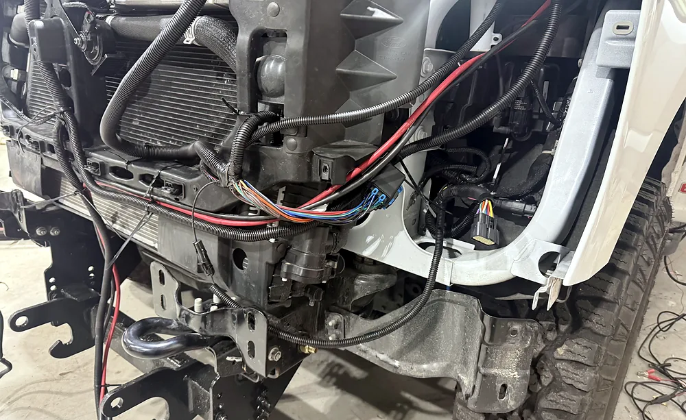 Front-end wiring harness with connectors and battery leads exposed during auto electrical repair