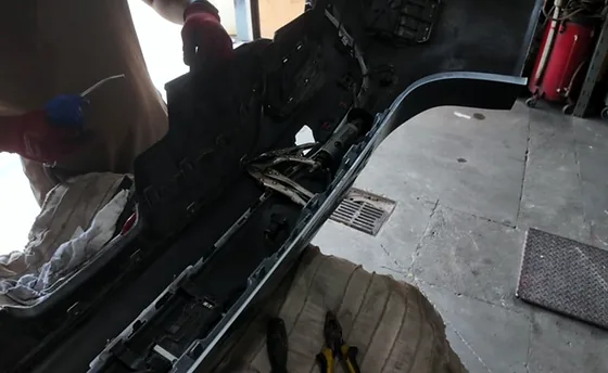 Technician working the inner structure and wiring of a detached rear bumper cover at Sultan Motors