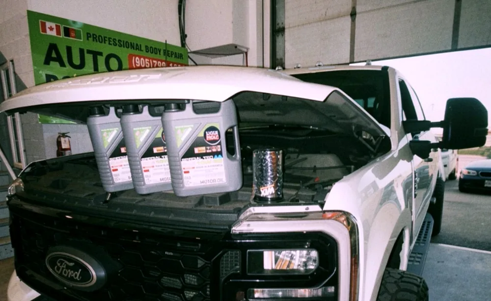 Fresh engine oil ready beside a pickup truck during scheduled maintenance at Sultan Motors