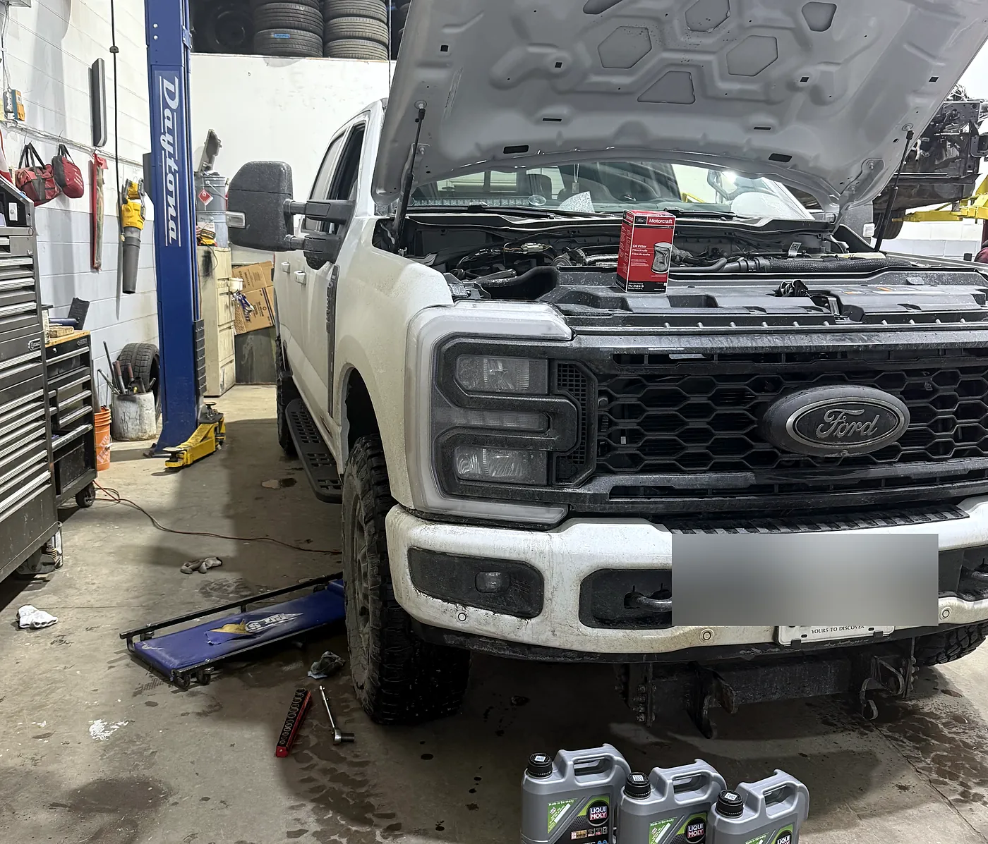 Pickup truck on the hoist with the hood open and fresh engine oil ready for an oil change at Sultan Motors