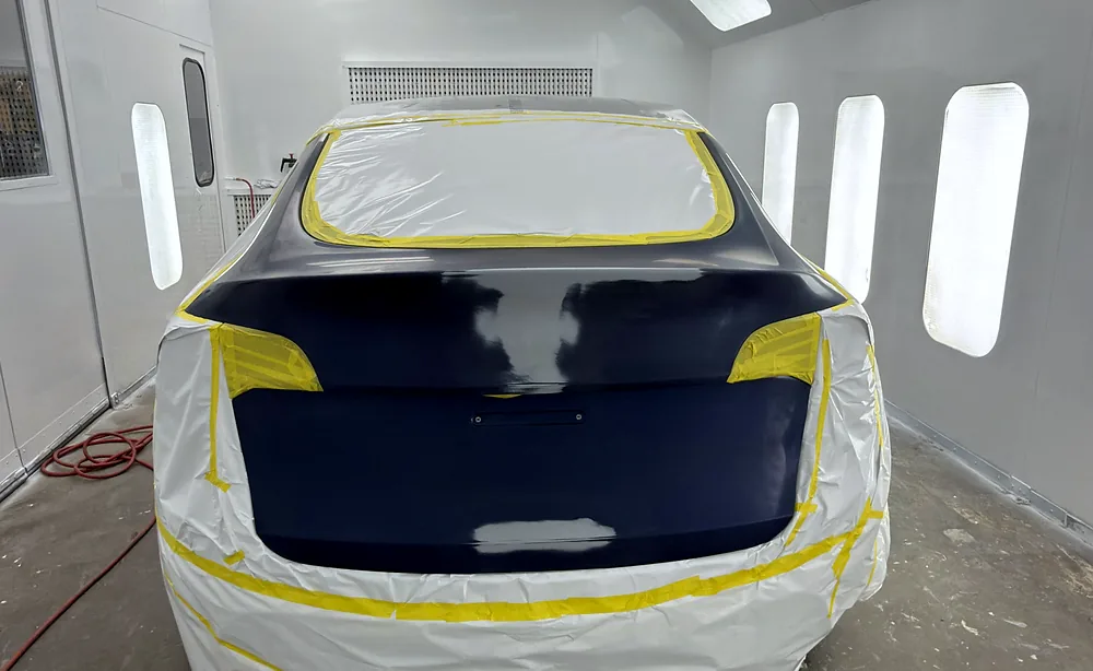 Masked rear end of a hatchback prepared for refinishing inside the Sultan Motors paint booth
