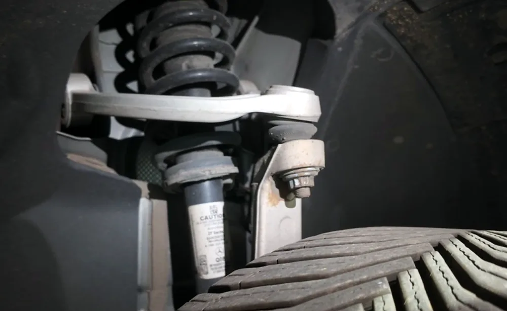Front strut and coil spring assembly photographed in the wheel arch during suspension service