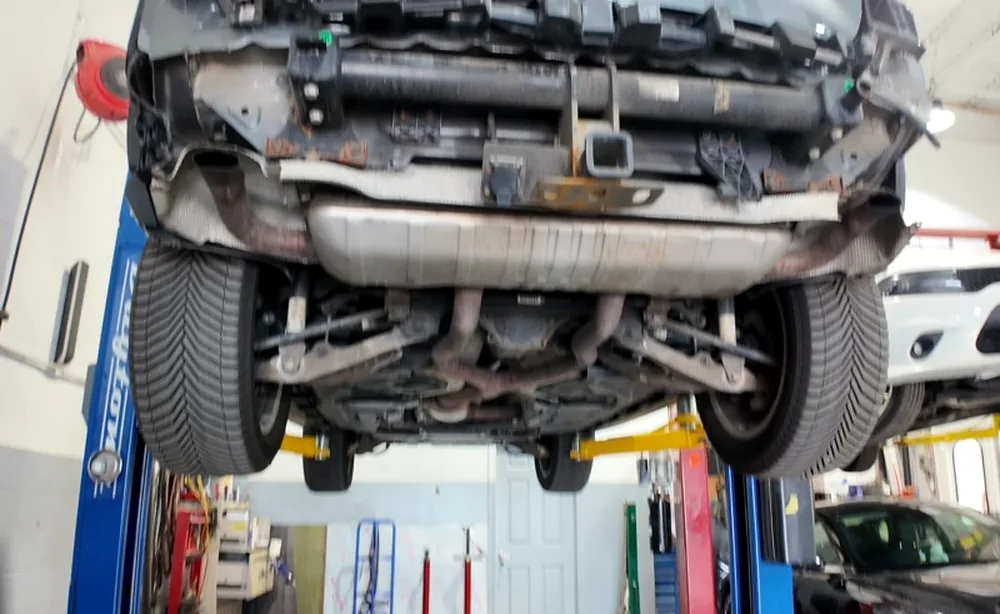 Close underbody view showing the driveline, subframe and exhaust beneath a lifted vehicle