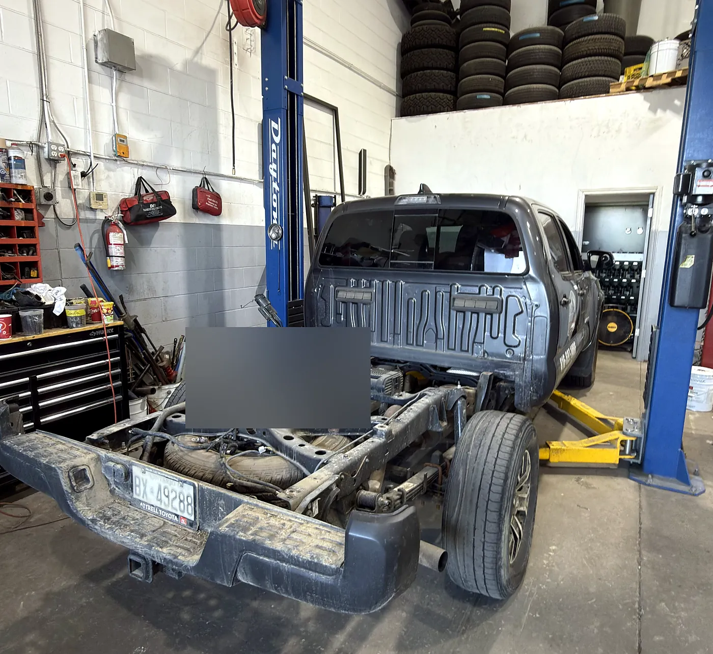 Pickup truck on a two-post hoist with the bed removed, exposing frame rails, rear axle and driveshaft at Sultan Motors